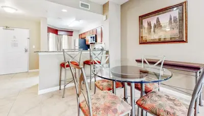 a dining room with a glass table and stools at Worldquest Resort Luxurious Pet Friendly Condo in Orlando
