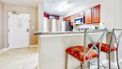a kitchen with two chairs at a bar with a counter at Worldquest Resort Luxurious Pet Friendly Condo in Orlando