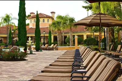 a bench with an umbrella and chairs and a building at Worldquest Resort Luxurious Pet Friendly Condo in Orlando