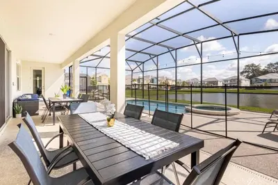 a patio with a table and chairs and a pool at Sleeps 36 | 15 Bedroom! Theater! Resort! POOL! in Kissimmee