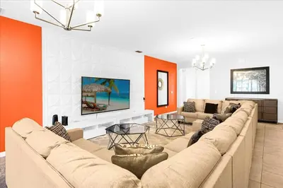 a living room with a large couch and an orange wall at Sleeps 36 | 15 Bedroom! Theater! Resort! POOL! in Kissimmee