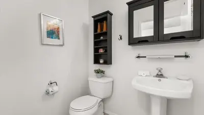 a bathroom with a toilet and a sink and a mirror at Upstay 3BR Family-Friendly Stylish Retreat w Patio in Kissimmee