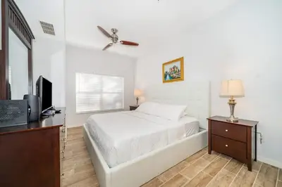 a white bedroom with a bed and a television at Charming 3BrTownhome near Disney in Kissimmee