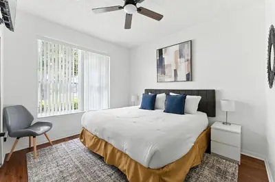 a white bedroom with a bed and a chair at Casa térrea c/ piscina e 2 suítes, sem carpete in Kissimmee