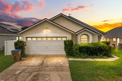 a house with a garage with a sunset in the background at Residentas Indian Creek in Kissimmee