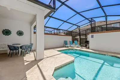 a swimming pool with a patio with chairs and a table at 4BR Pool Home Ideal for Families in Kissimmee