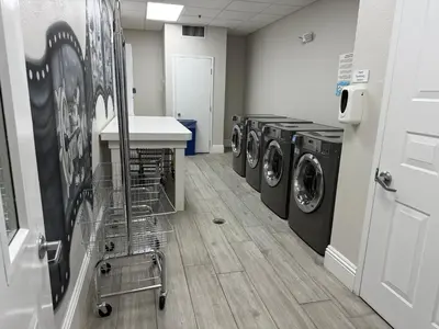 a laundry room with three washing machines and a cart at 110 - Next to Disney - Pool in Orlando