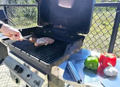 a person cooking a piece of meat on a grill at Stunning waterfront Views 1 mile to Disney 2 bath in Orlando