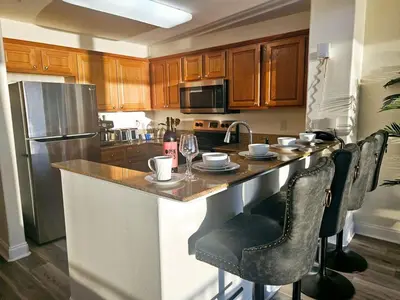 a kitchen with a counter with chairs and a refrigerator at Stunning waterfront Views 1 mile to Disney 2 bath in Orlando