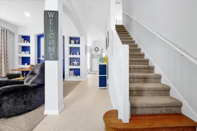 a staircase in a living room with blue and white walls at Emerald Island Resort 6 Bed Pool & Spa villa in Kissimmee
