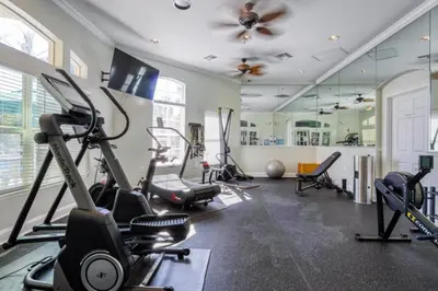 a gym with cardio equipment and a ceiling fan at Emerald Island Resort 6 Bed Pool & Spa villa in Kissimmee