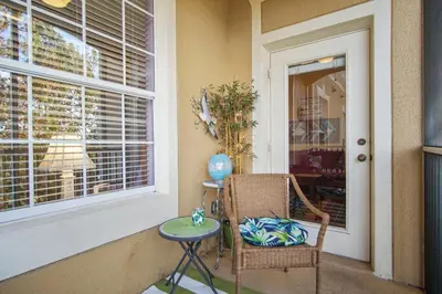 a porch with a chair and a table and a window at Palm Tree Paradise 3 bedroom condo at Windsor Hills close to Disney in Orlando