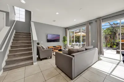a living room with a couch and a staircase at Beautiful 3 Bedroom Villa with Private Hot Tub, 10 mins to Disney! in Kissimmee