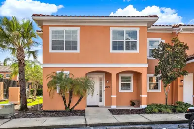 a orange house with palm trees in front of it at Beautiful 3 Bedroom Villa with Private Hot Tub, 10 mins to Disney! in Kissimmee