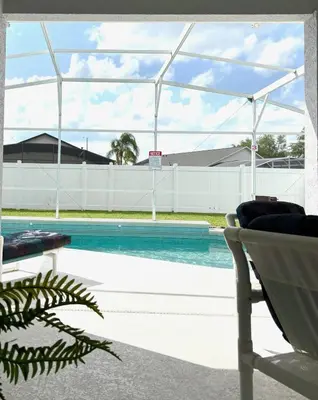 a swimming pool with a chair next to a white fence at Family Home, Near Disney-Private pool, Spacious 3BR Retreat in Orlando