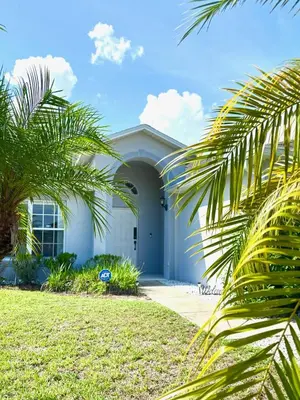 a white house with palm trees in front of it at Family Home, Near Disney-Private pool, Spacious 3BR Retreat in Orlando