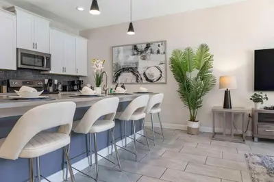 a kitchen with a bar with white stools at Family Stylish 4BR Pool Townhome Storey Lake in Kissimmee