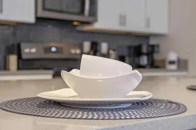 a white bowl on a plate on a counter in a kitchen at Family Stylish 4BR Pool Townhome Storey Lake in Kissimmee