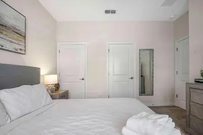 a white bedroom with a bed and a mirror at Family Stylish 4BR Pool Townhome Storey Lake in Kissimmee
