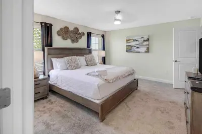 a bedroom with a large bed and a dresser in it at Family Stylish 4BR Pool Townhome Storey Lake in Kissimmee