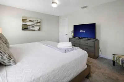 a bedroom with a bed and a flat screen tv at Family Stylish 4BR Pool Townhome Storey Lake in Kissimmee