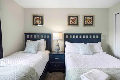 a bedroom with two beds and a lamp on a night stand at Family Stylish 4BR Pool Townhome Storey Lake in Kissimmee
