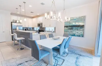 a kitchen and dining room with a white table and blue chairs at Elsa's Enchanting Escape just 15 minutes to Disney in Kissimmee
