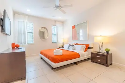 a bedroom with a bed with orange sheets and a ceiling fan at Elsa's Enchanting Escape just 15 minutes to Disney in Kissimmee