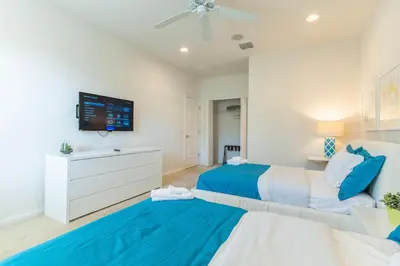 a bedroom with two beds and a flat screen tv at Elsa's Enchanting Escape just 15 minutes to Disney in Kissimmee