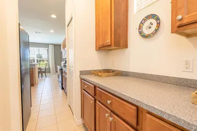 a kitchen with wooden cabinets and a clock on the wall at 6BR Fun Villa – Game Room, Pool, Near Parks in Kissimmee