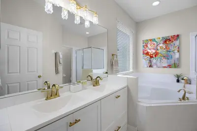 a white bathroom with two sinks and a mirror at Luxurious Family Resort Getaway in Kissimmee