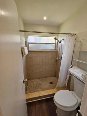 a small bathroom with a toilet and a shower at Magical Getaway- Cozy Home Minutes from Disney, Restaurants & Outlets! in Kissimmee