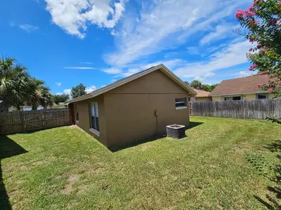 a house in a yard with a fence at Magical Getaway- Cozy Home Minutes from Disney, Restaurants & Outlets! in Kissimmee