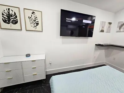 a white room with a bed and a flat screen tv at Comfy Tiny Home WP Large Private Deck Queen bed in Orlando