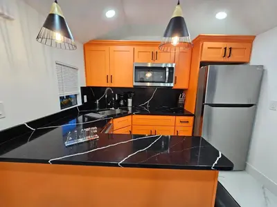 a kitchen with orange cabinets and a black counter top at Comfy Tiny Home WP Large Private Deck Queen bed in Orlando