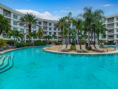 a large swimming pool with chairs and a building at Spacious Pet Friendly in Orlando