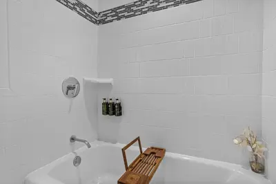 a white bathroom with a tub with a bench in it at Spacious Pet Friendly in Orlando