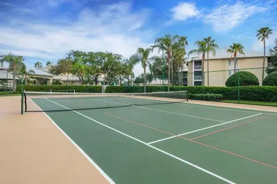 a tennis court in front of a building with palm trees at Hilton Vacation Club Cypress Pointe Orlando in Orlando