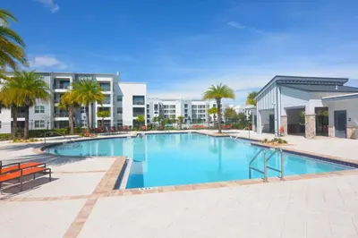 a large swimming pool with palm trees and buildings at Storey Lake Resort Condo next to Disney in Kissimmee