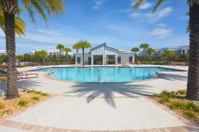 a swimming pool with palm trees and a building at Storey Lake Resort Condo next to Disney in Kissimmee