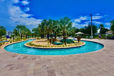 a large pool with palm trees in a park at Storey Lake Resort Condo next to Disney in Kissimmee