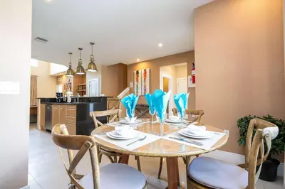 a dining room with a table and chairs and a kitchen at Modern Magic Village Home for 12 with Grill 3131 in Orlando