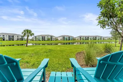 a view of the apartment buildings from the lawn with blue chairs at Waves of Relaxation - For 8 in Orlando