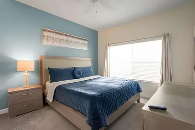 a bedroom with a bed with a blue comforter and a window at Magia 4Q c/ Piscina e Quartos Temáticos Disney in Kissimmee