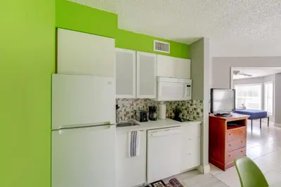 a kitchen with white cabinets and a green wall at 2 Mi to Disney and Old Town Resort Condo with Perks in Orlando