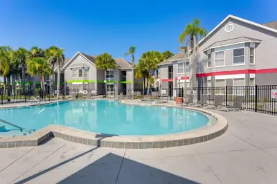 a swimming pool in a apartment complex with palm trees at 2 Mi to Disney Resort Condo with Pool Access in Orlando