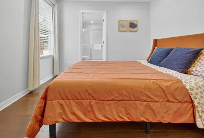 a bedroom with a bed with an orange bedspread at 290 LF - BellaVida Cozy 6BR Pool Home in Kissimmee