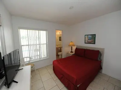 a bedroom with a red bed and a television at Holiday Hideout in Orlando