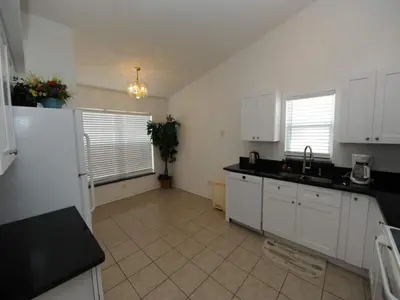 a kitchen with white cabinets and a tile floor at Holiday Hideout in Orlando