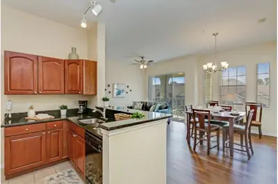 a kitchen with wooden cabinets and a dining room with a table at Two-Bedroom Townhome Kissimmee in Orlando